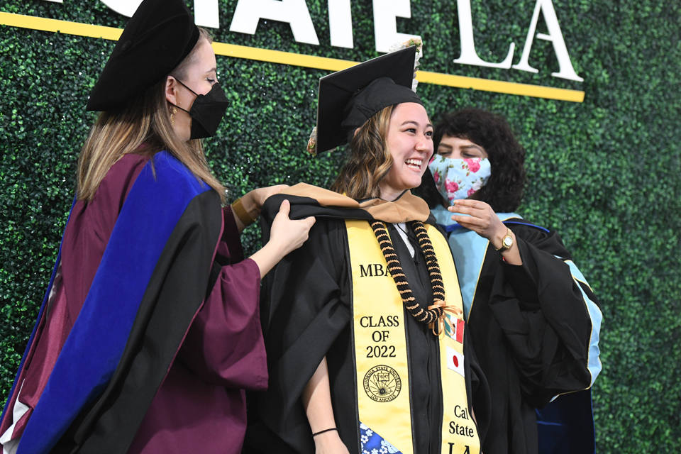 Mylissa Magallanes gets hooded onstage during a morning College of Business and Economics Commencement ceremony