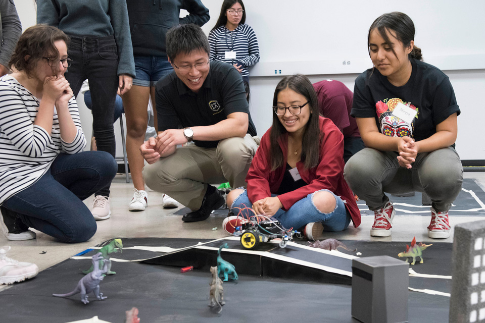 Students and a professors working with small electronic car.