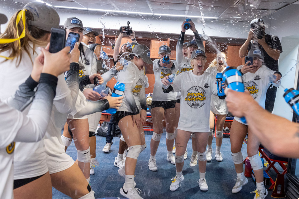 Women's Volleyball team celebrating their championship victory in the locker room.