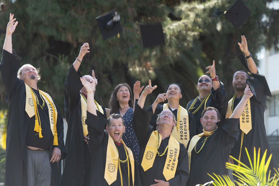 Graduates tossing their graduation caps into the air.