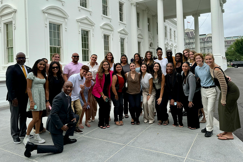 A group of people pose together for a photo at the White House.