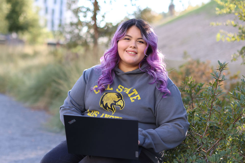 A student sitting outside using their laptop.