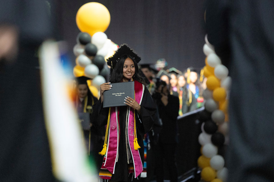 A student holds up their diploma.