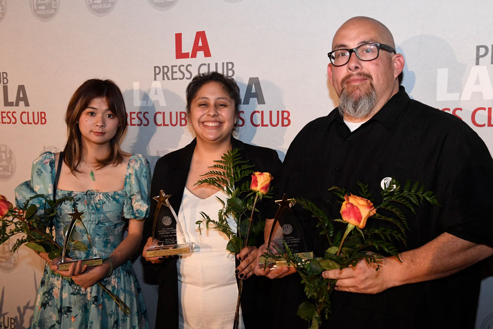 Three people holding awards and flowers they had just received.