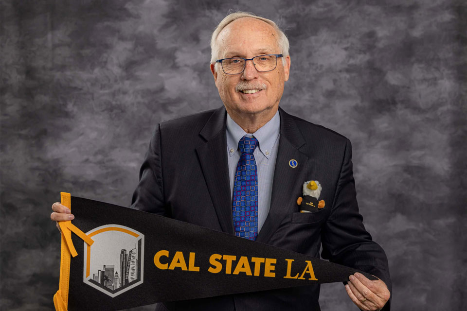 Larry Adamson holds up a Cal State LA pennant.