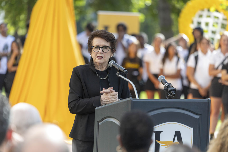 Billie Jean King speaking from behind podium.