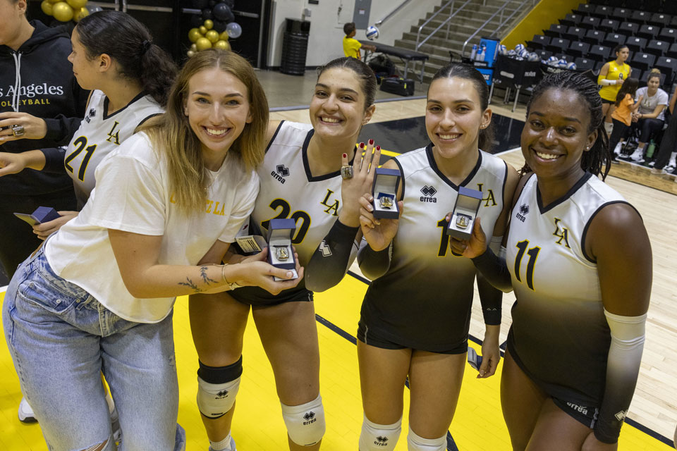 Cal State LA Women's Volleyball team members showing their NCAA Championship rings.