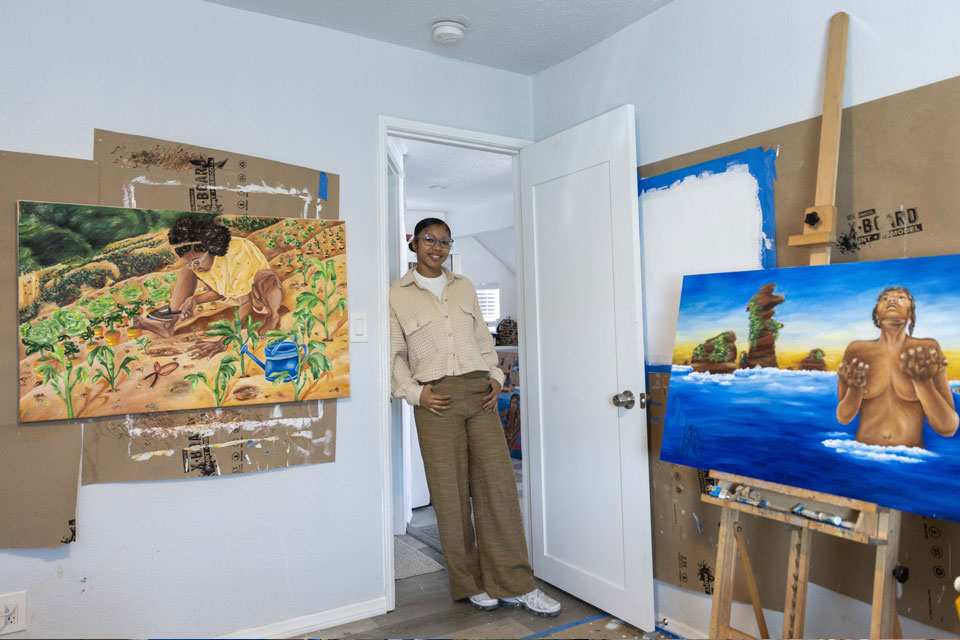 A person standing in a doorway next to two paintings.