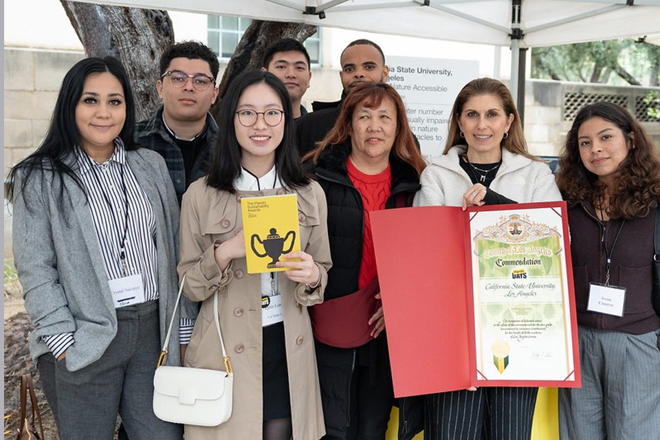 A group of students and faculty pose together for a photo while holding an award certificate.