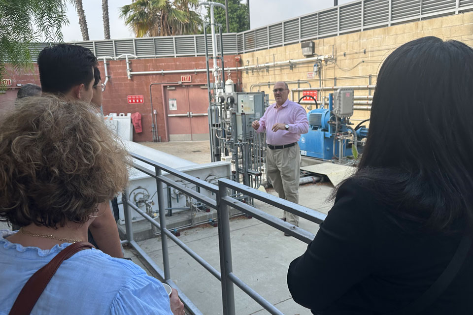 A Cal State LA representative speaks to Move LA visitors during a guided tour of the Hydrogen Research Facility's outdoor operations area.