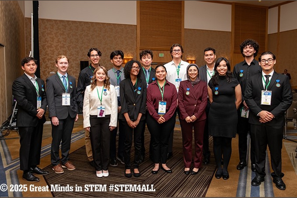 Group of Cal State LA students pose together at the 2025 Great Minds in STEM conference, wearing conference badges and professional attire with #STEM4ALL signage in the background. 