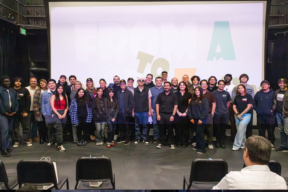 Students posing for a group photo in front of a display board.