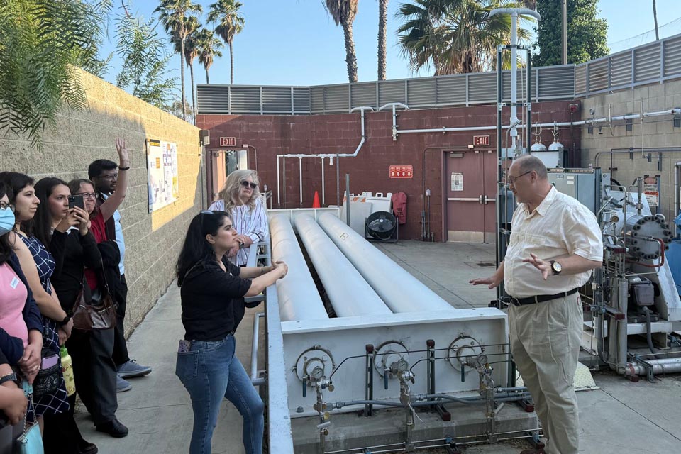 A group of students and faculty listen during an outdoor engineering lab tour as an instructor explains equipment.