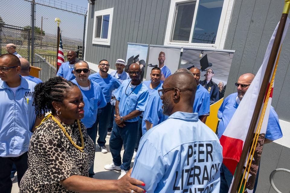 Cheerleaders and community members dance in the street during the MLK Day Parade, with palm trees and campus buildings in the background.