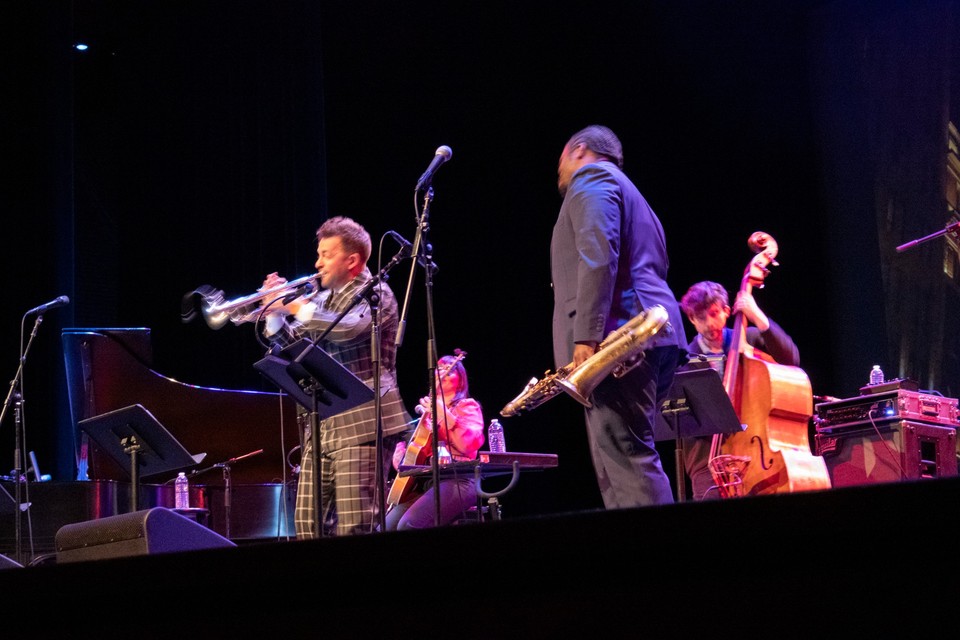 Jazz musicians perform onstage with trumpet, saxophone, and bass under stage lighting at Cal State LA.