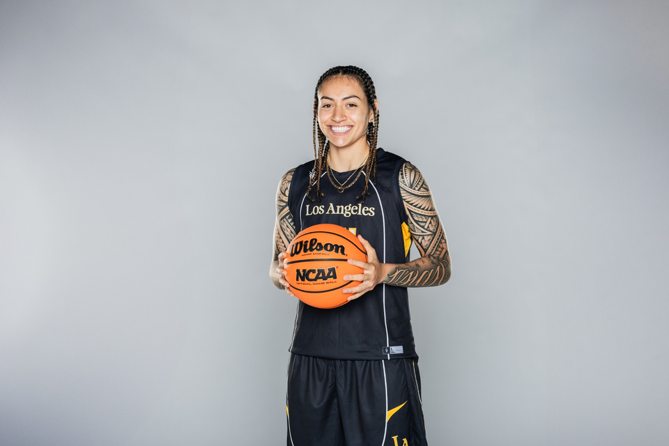 Cal State LA women’s basketball player poses in uniform holding an NCAA basketball against a neutral background.
