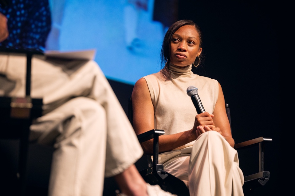 Speaker holds a microphone while seated on stage during a panel conversation at Cal State LA.