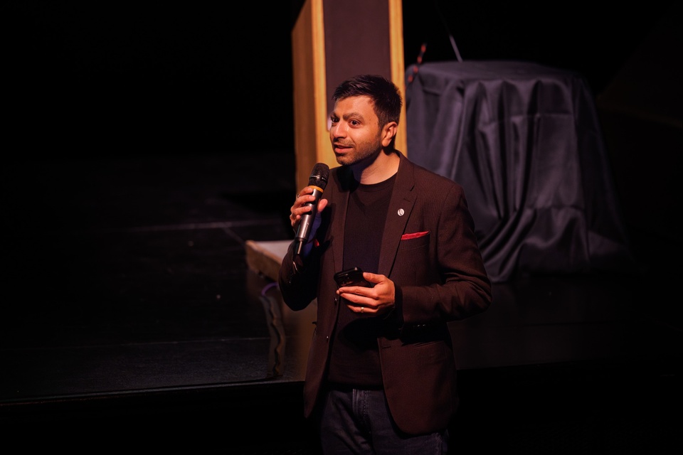 Speaker holds a microphone while addressing attendees during an AI Filmmaker Symposium event at Cal State LA.
