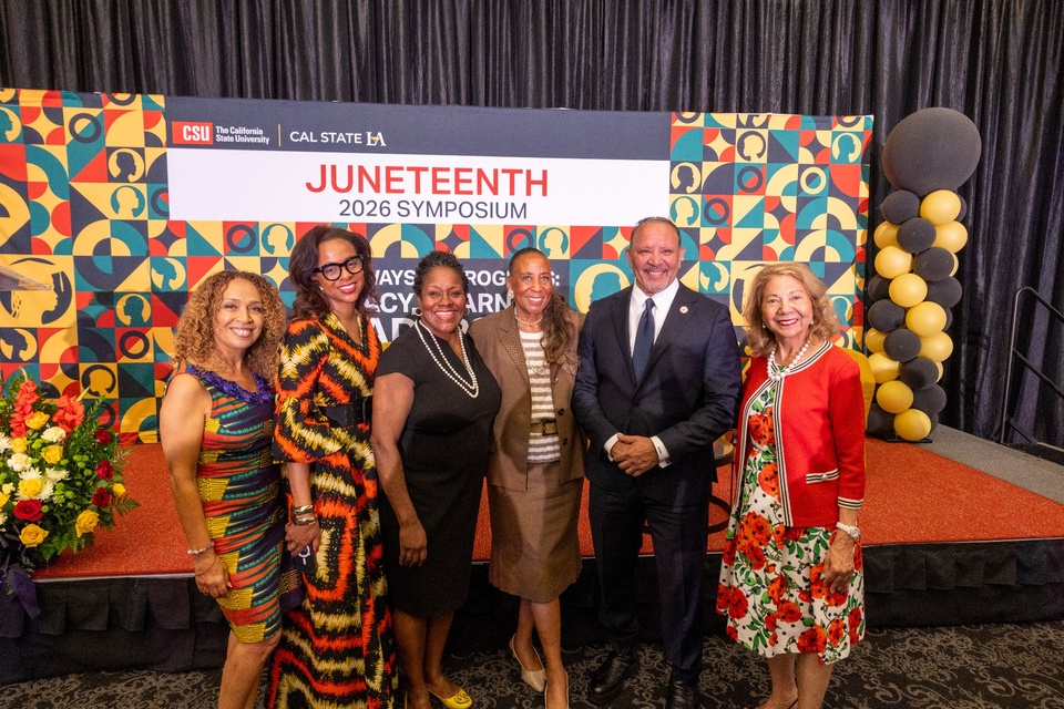 Attendees pose together in front of a Juneteenth 2026 Symposium backdrop during an event at Cal State LA.