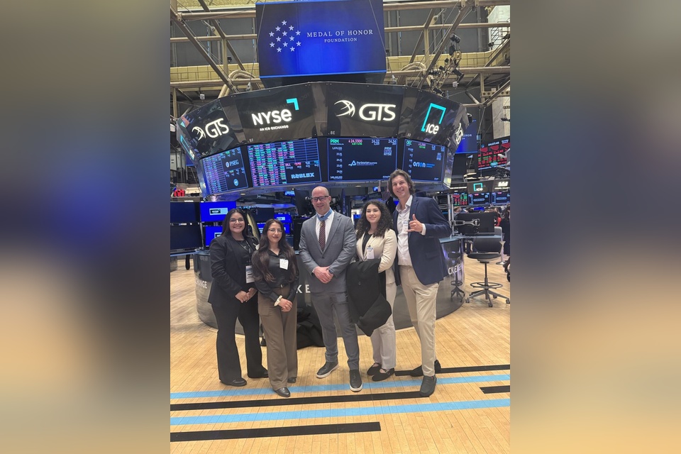 Group of students and a faculty representative pose on the floor of the New York Stock Exchange.