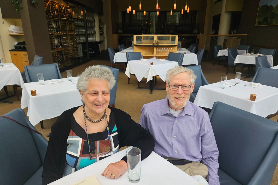 Two donors smile while seated together at a table inside a restaurant.