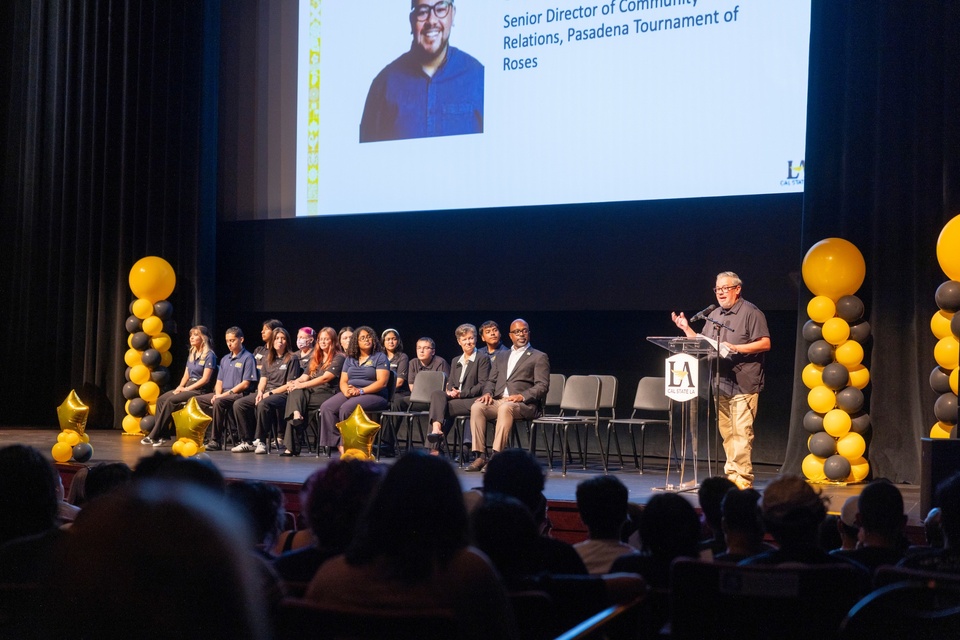 Speaker addresses students and guests from a podium as student leaders and university representatives sit on stage during Cal State LA Student Convocation 2026.