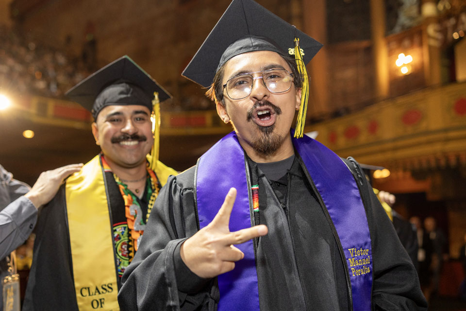 Two students at a graduation ceremony celebrating.