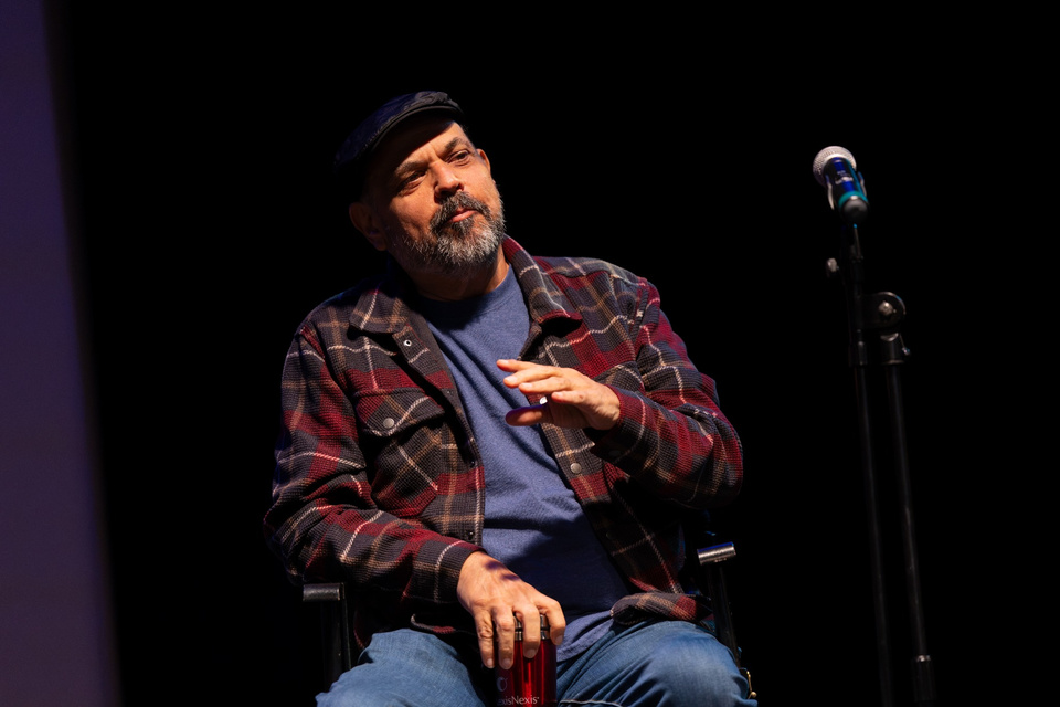 Frank Crim sits onstage beside a microphone and gestures during EagleCon at Cal State LA.